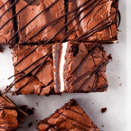 A sideways frozen cheesecake brownie leaning against more brownies.