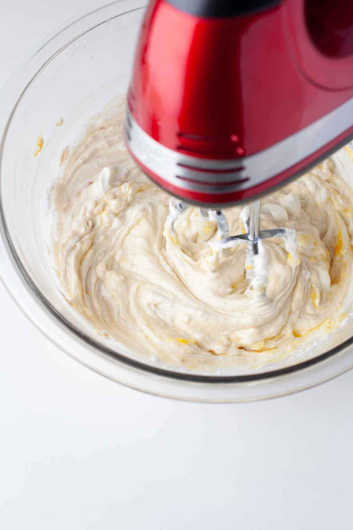 A hand mixer beating cream cheese mixture. 
