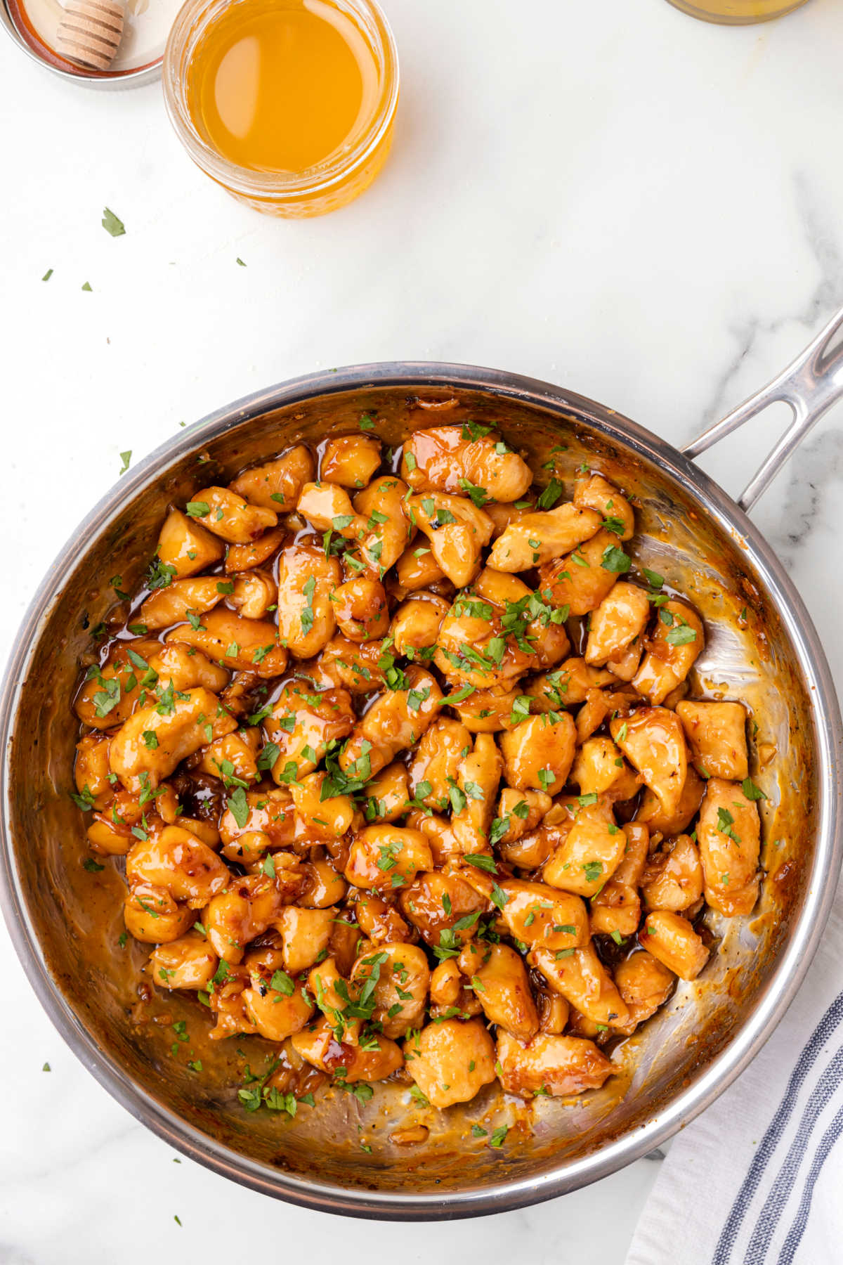 Honey garlic chicken in a skillet topped with parsley.