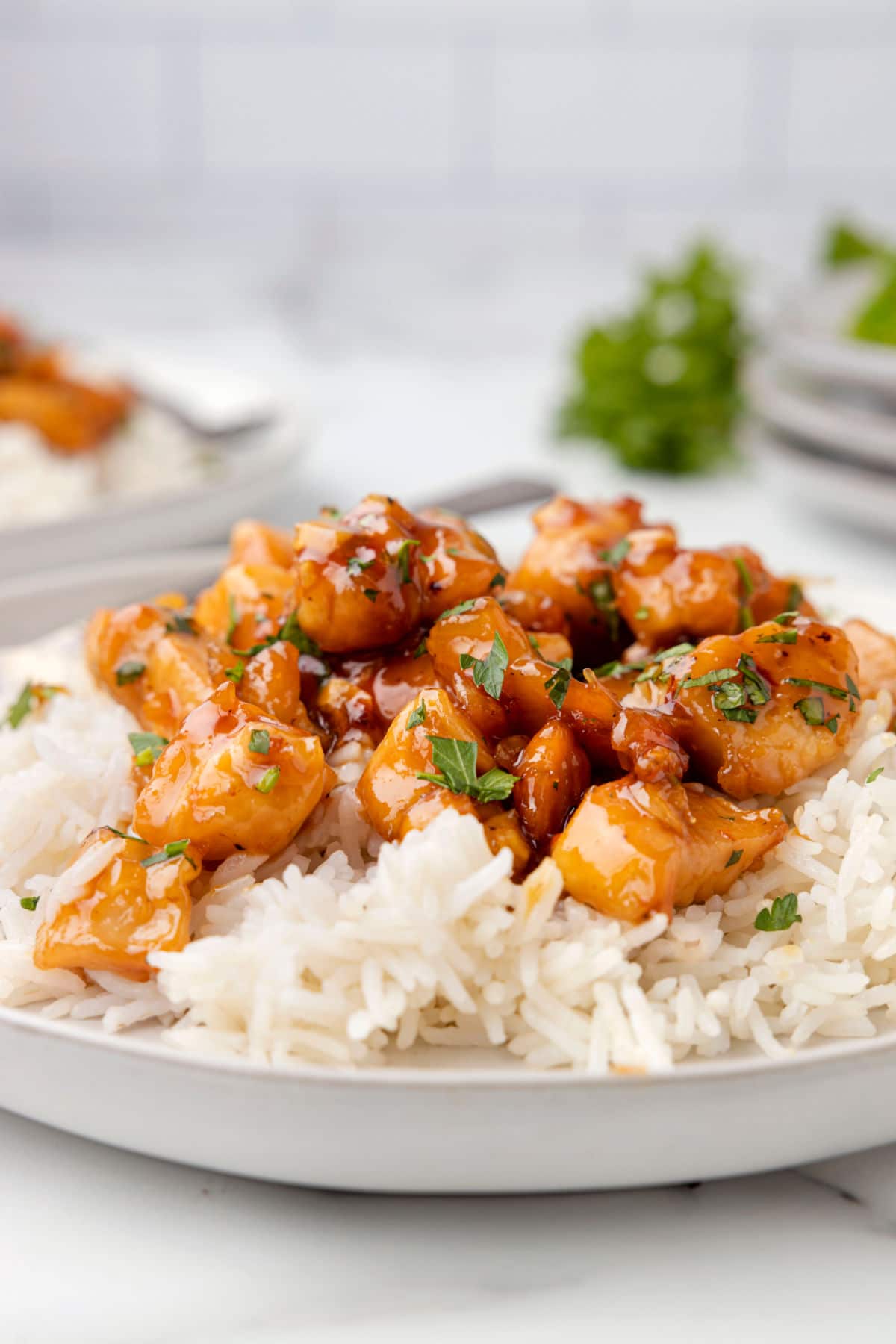 A plate of honey garlic chicken next to a second dish of honey garlic chicken.