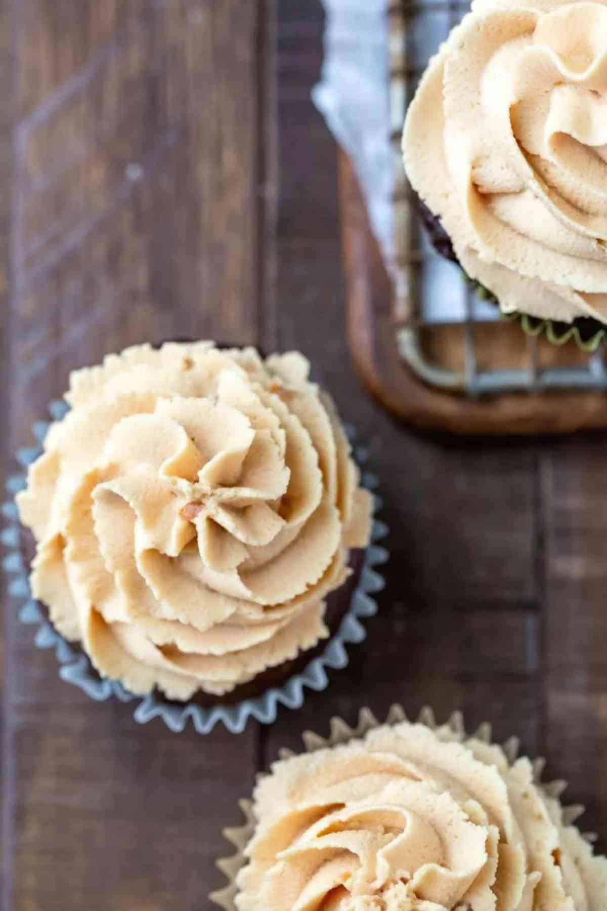 Peanut Butter Frosting Recipe Peanut butter frosting on chocolate cupcake on a wooden background.