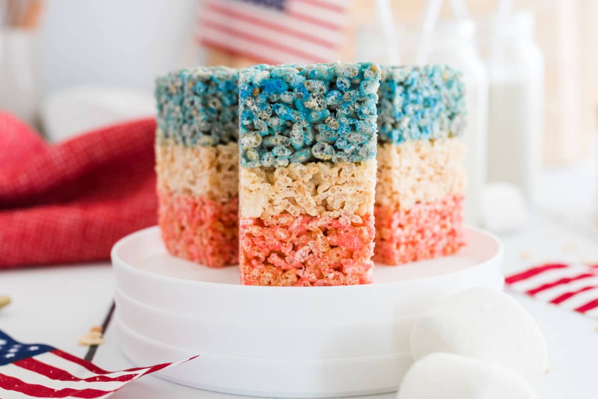 Three red white and blue rice krispies treats on white plates.