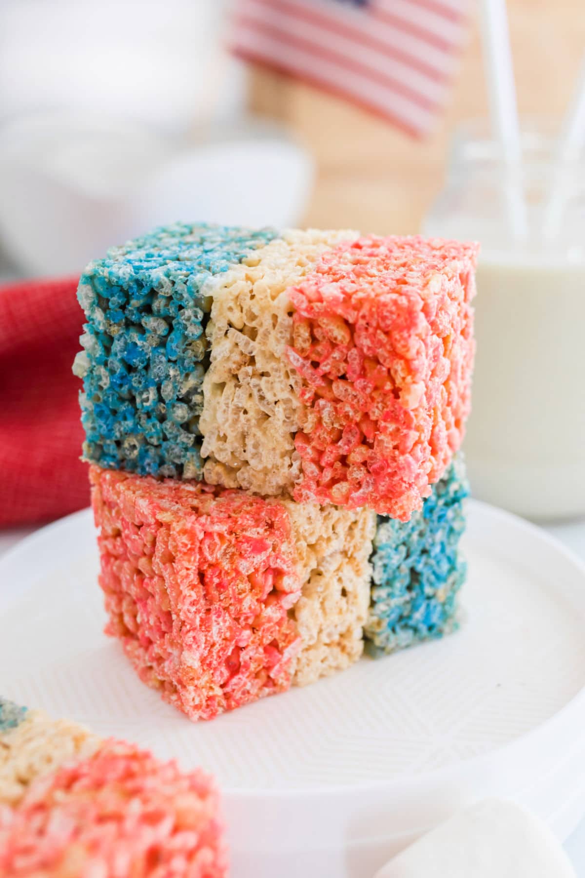 Two red white and blue rice krispies treats stack on each other on a white plate.