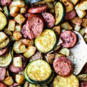 A tan spatula scooping up kielbasa zucchini and potatoes.