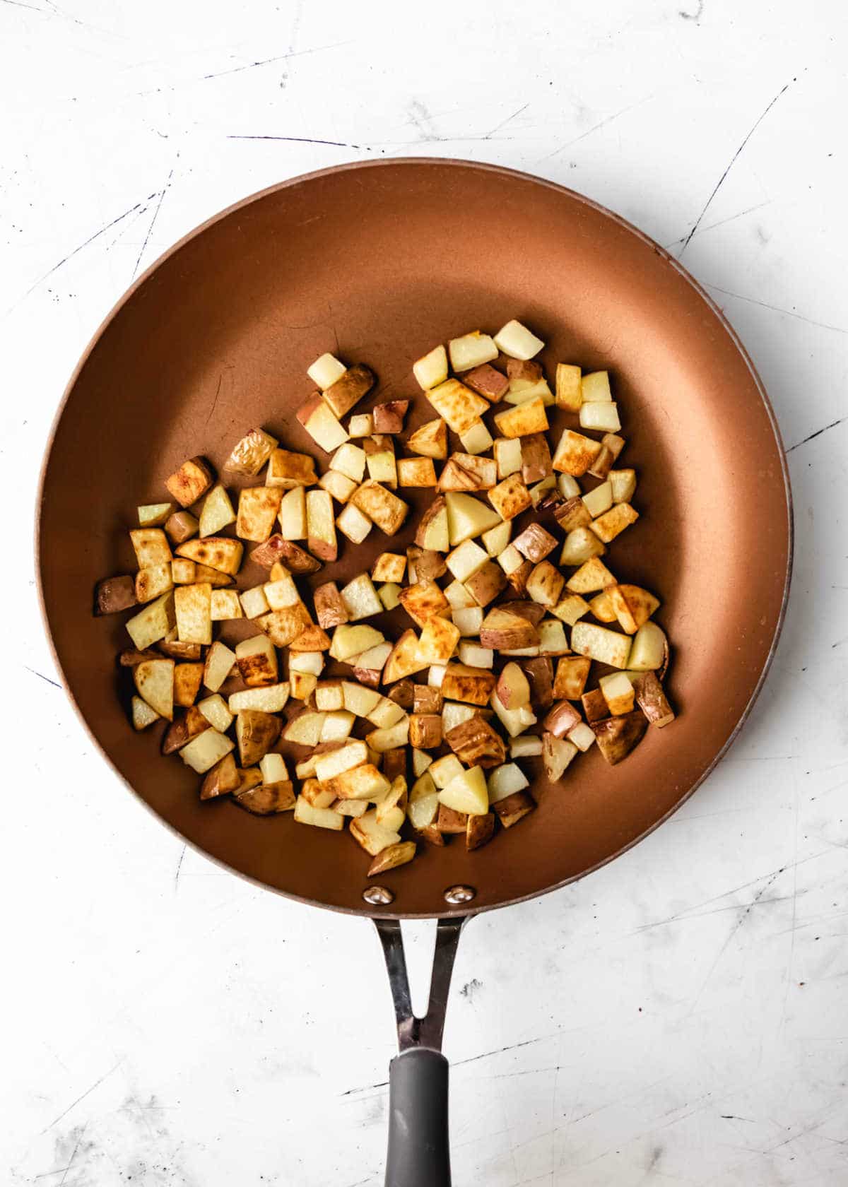 Cooked diced potatoes in a skillet. 