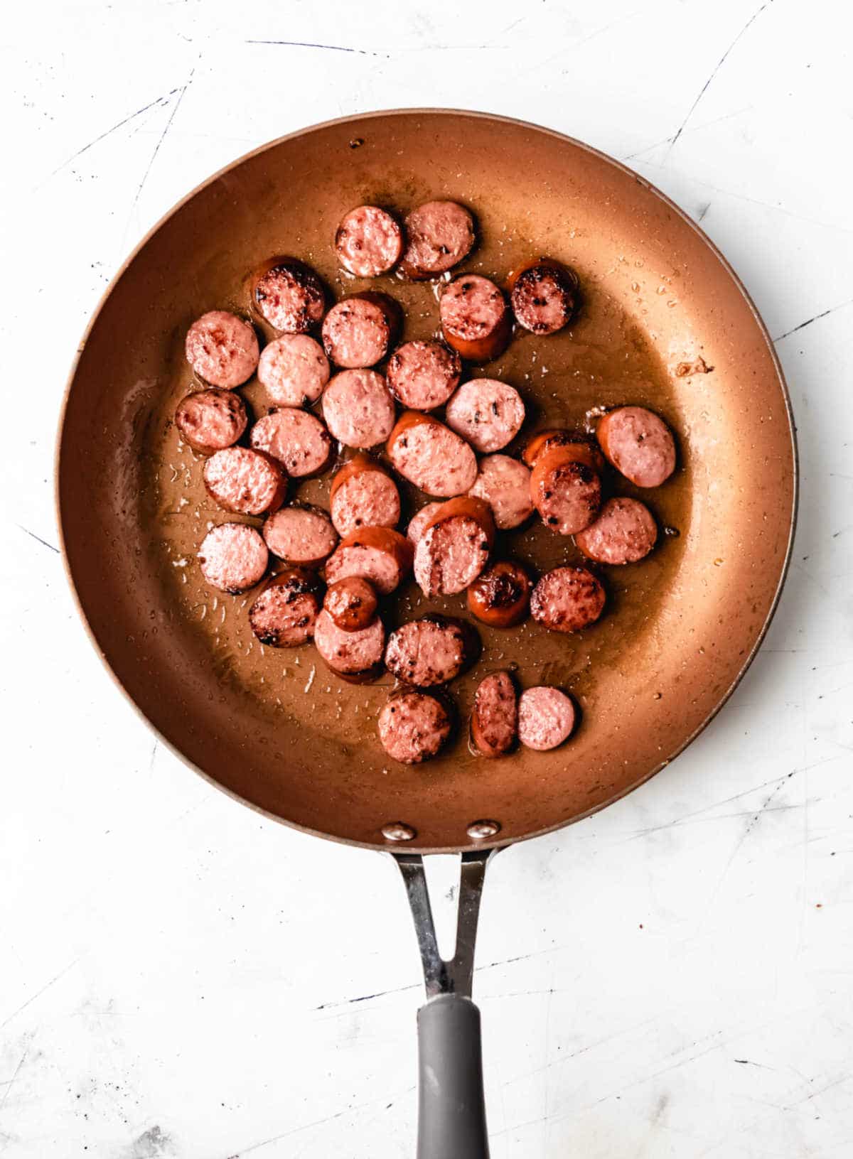 Kielbasa cooking in a skillet. 