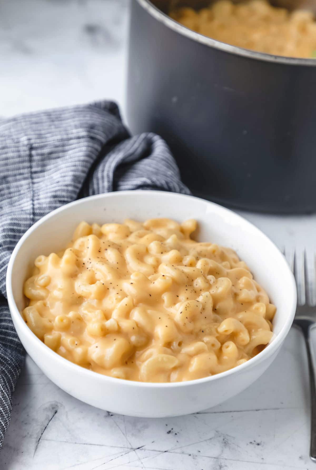 A bowl of homemade macaroni and cheese next to a saucepan.