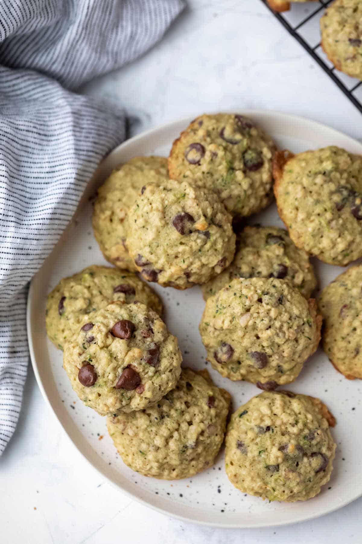 A plate of chocolate chip zucchini cookies next to a linen towel. 