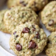 A plate of zucchini chocolate chip cookies with an upright cookie in the front.