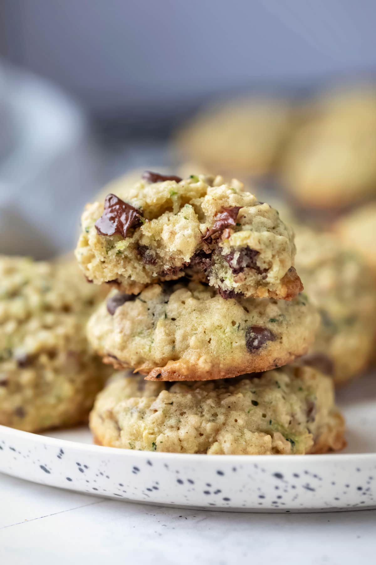 A stack of zucchini chocolate chip cookies topped with half a cookie. 