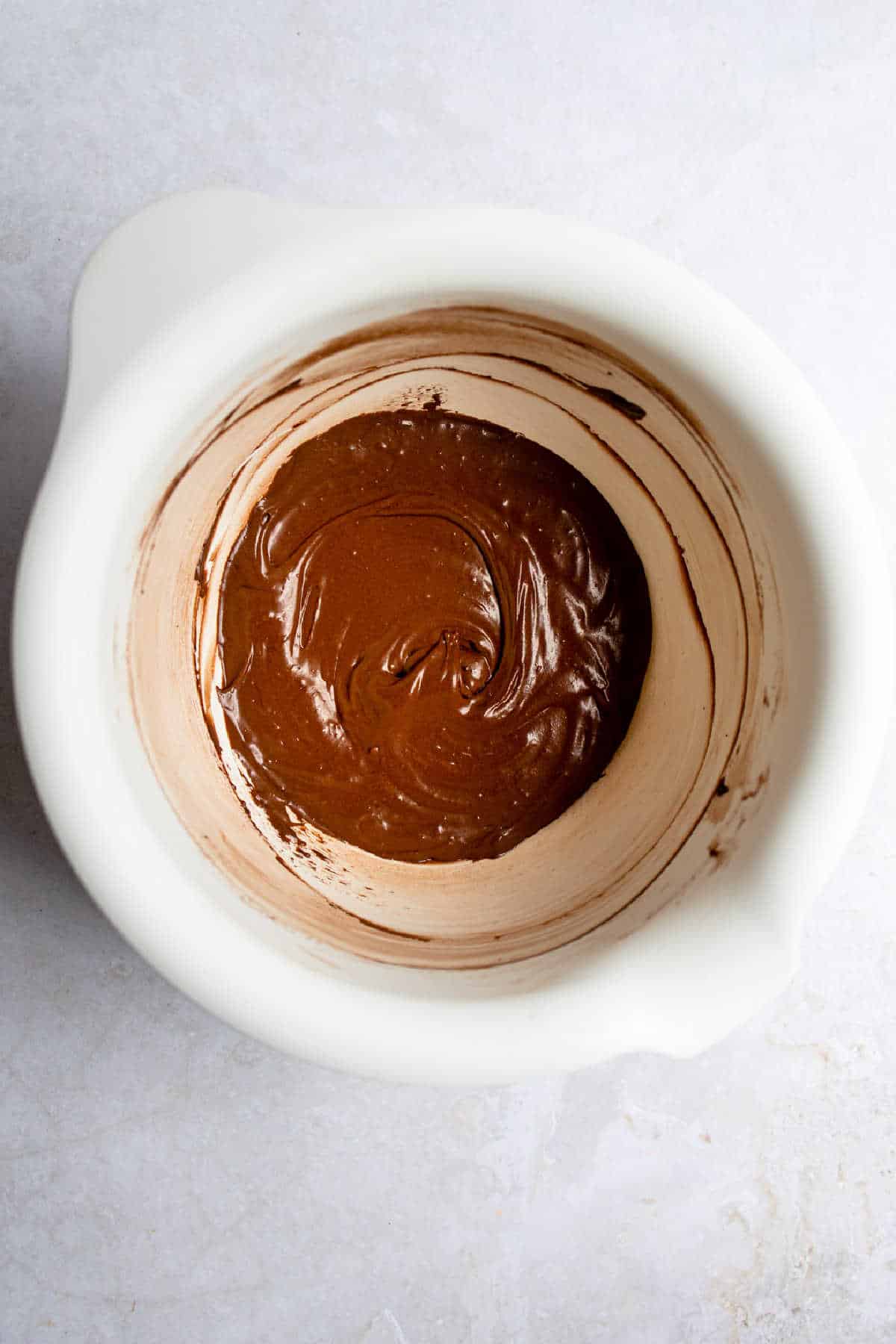 Chocolate frosting in a white mixing bowl. 