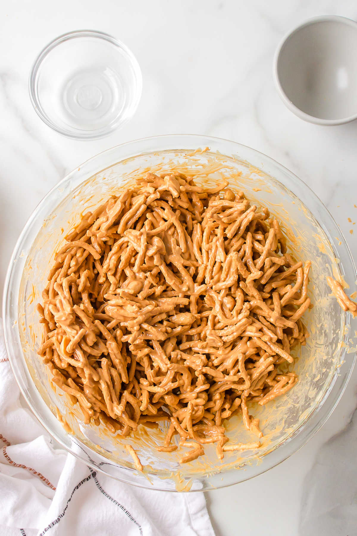 Butterscotch coated chow mein noodles in a glass mixing bowl. 