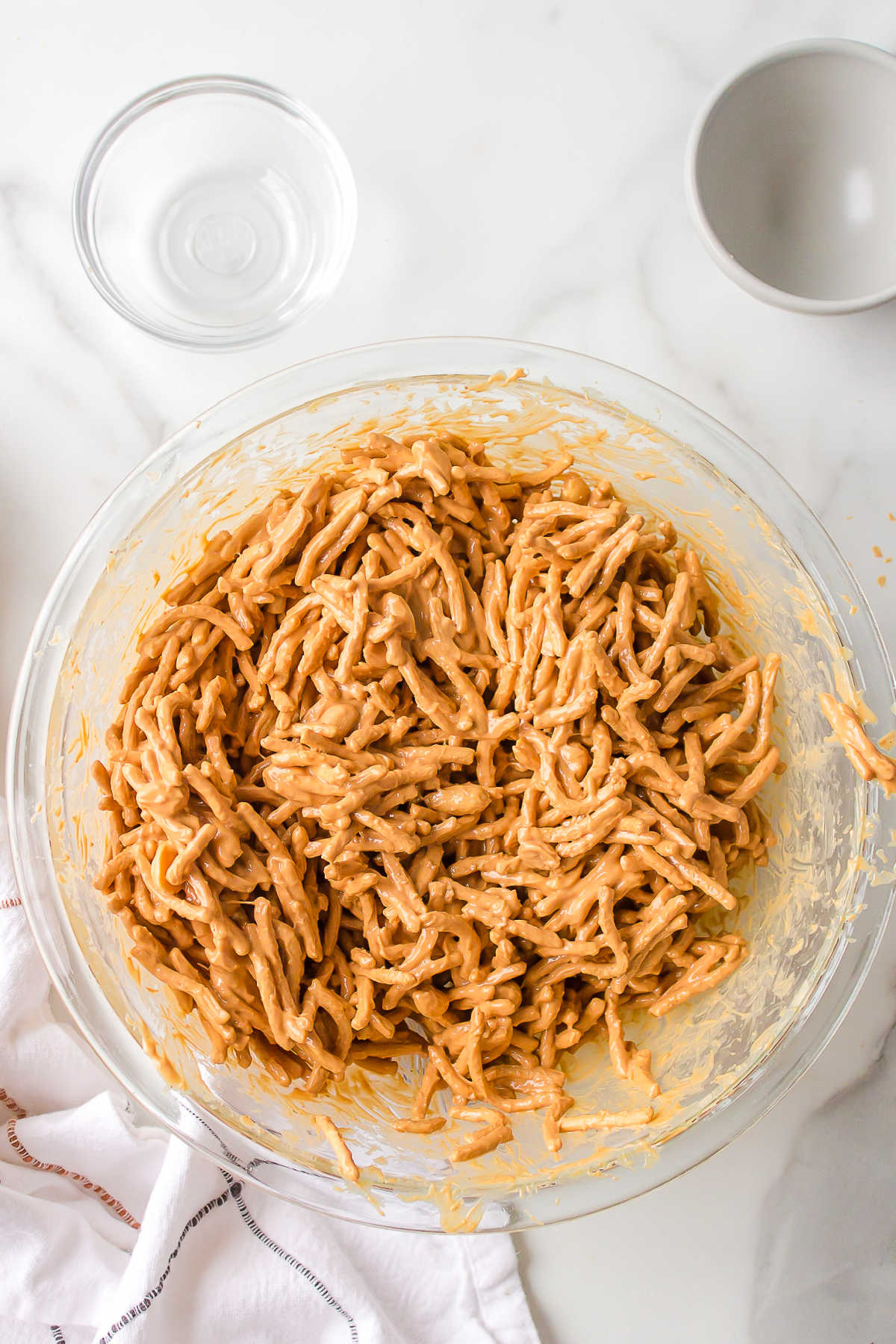 Butterscotch coated chow mein noodles in a glass mixing bowl.