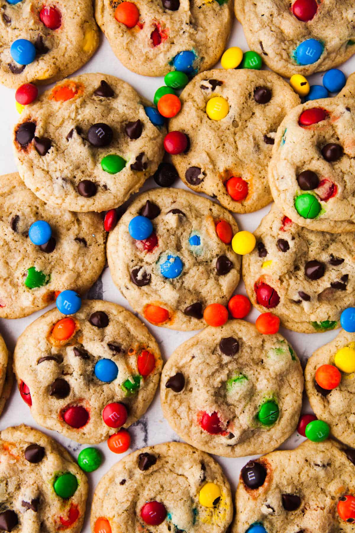 A piece of parchment paper covered with M&M cookies and M&Ms. 