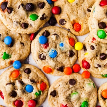 Overlapping M&M cookies with M&Ms scattered around.