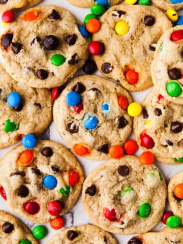 Overlapping M&M cookies with M&Ms scattered around.