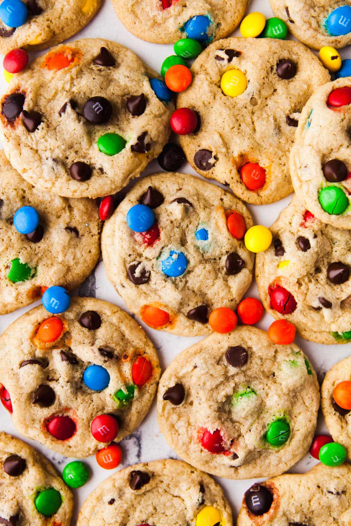 Overlapping M&M cookies with M&Ms scattered around. 