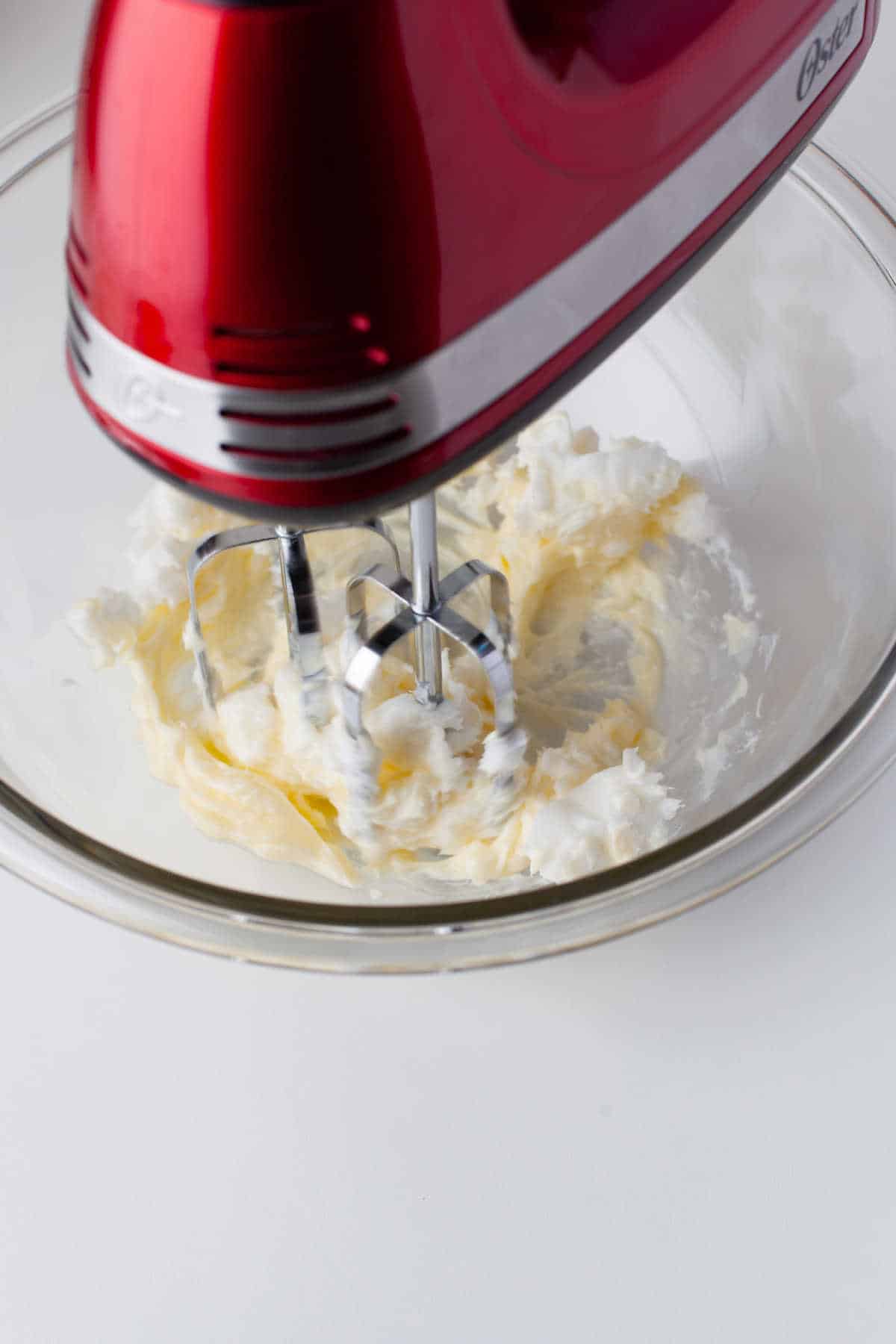 A hand mixer beating butter and shortening together.