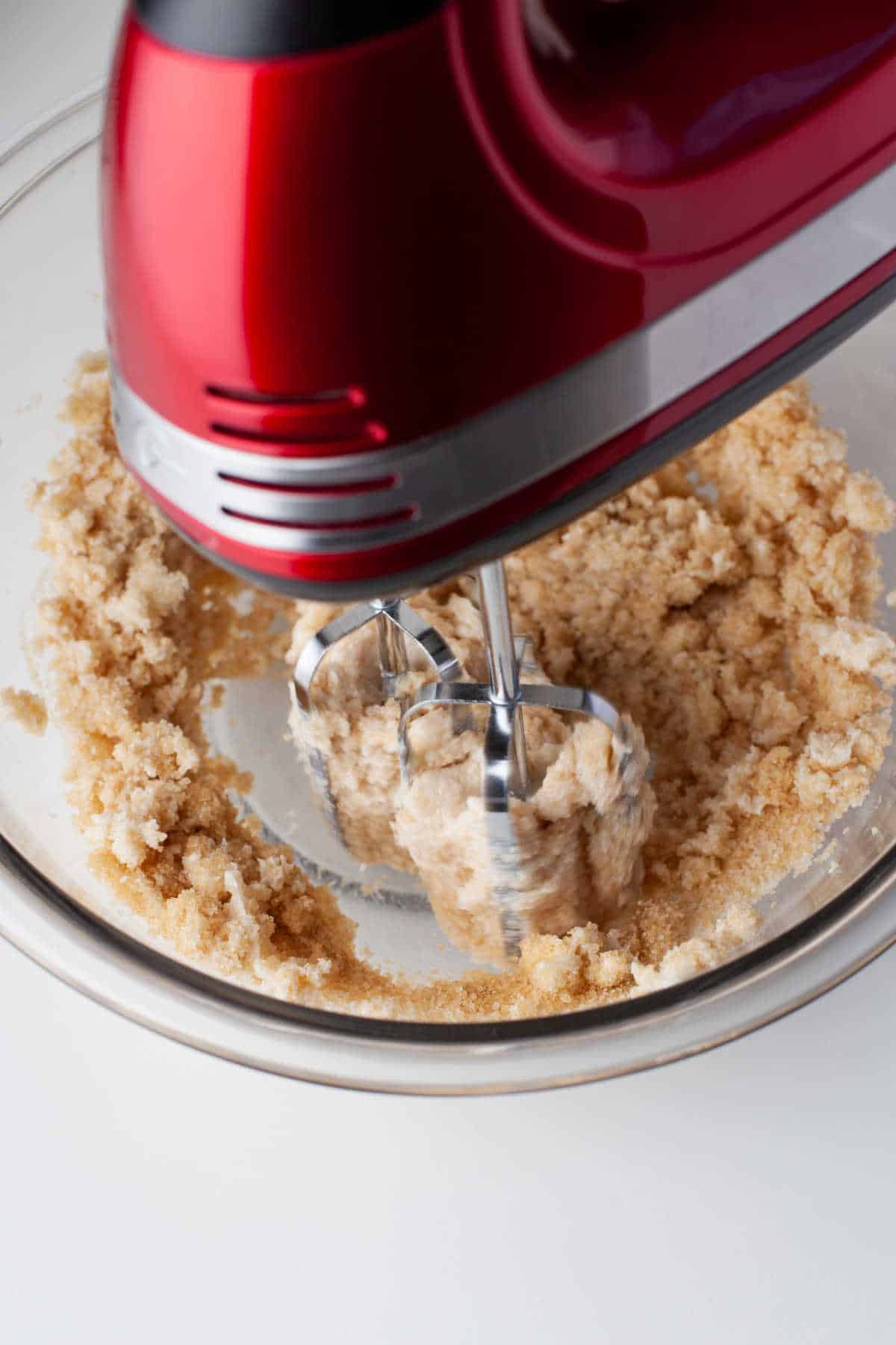 A hand mixer beating butter shortening and sugars together. 