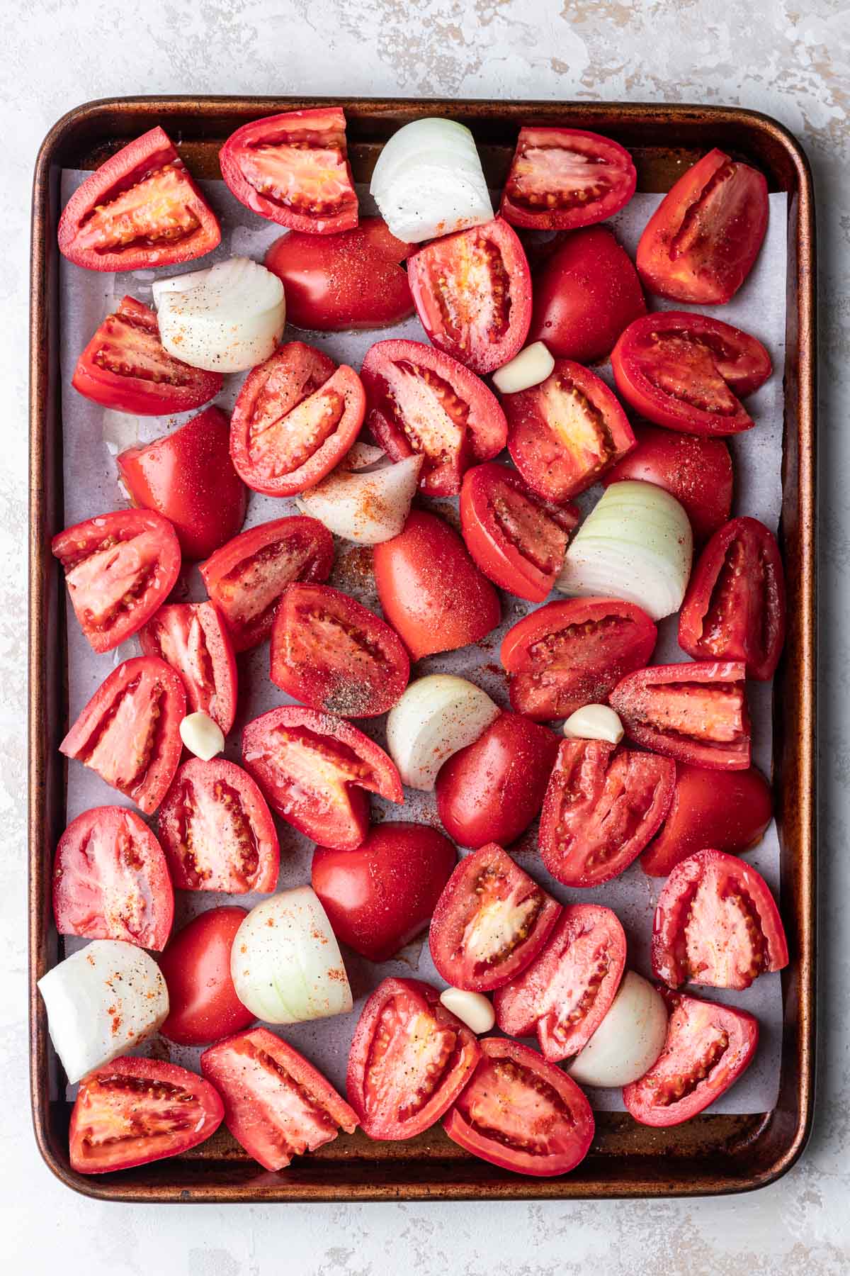 Tomato onion and garlic on a sheet pan.