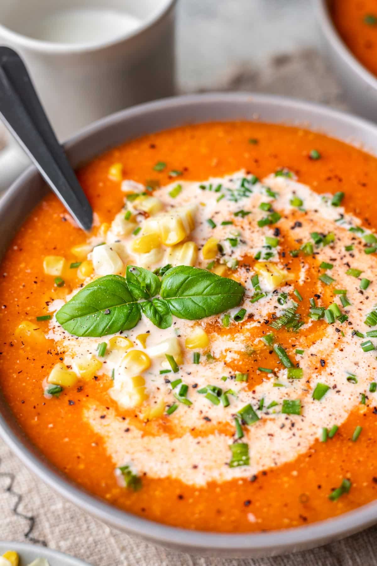 Close up photo of roast tomato and corn soup in a gray dish. 