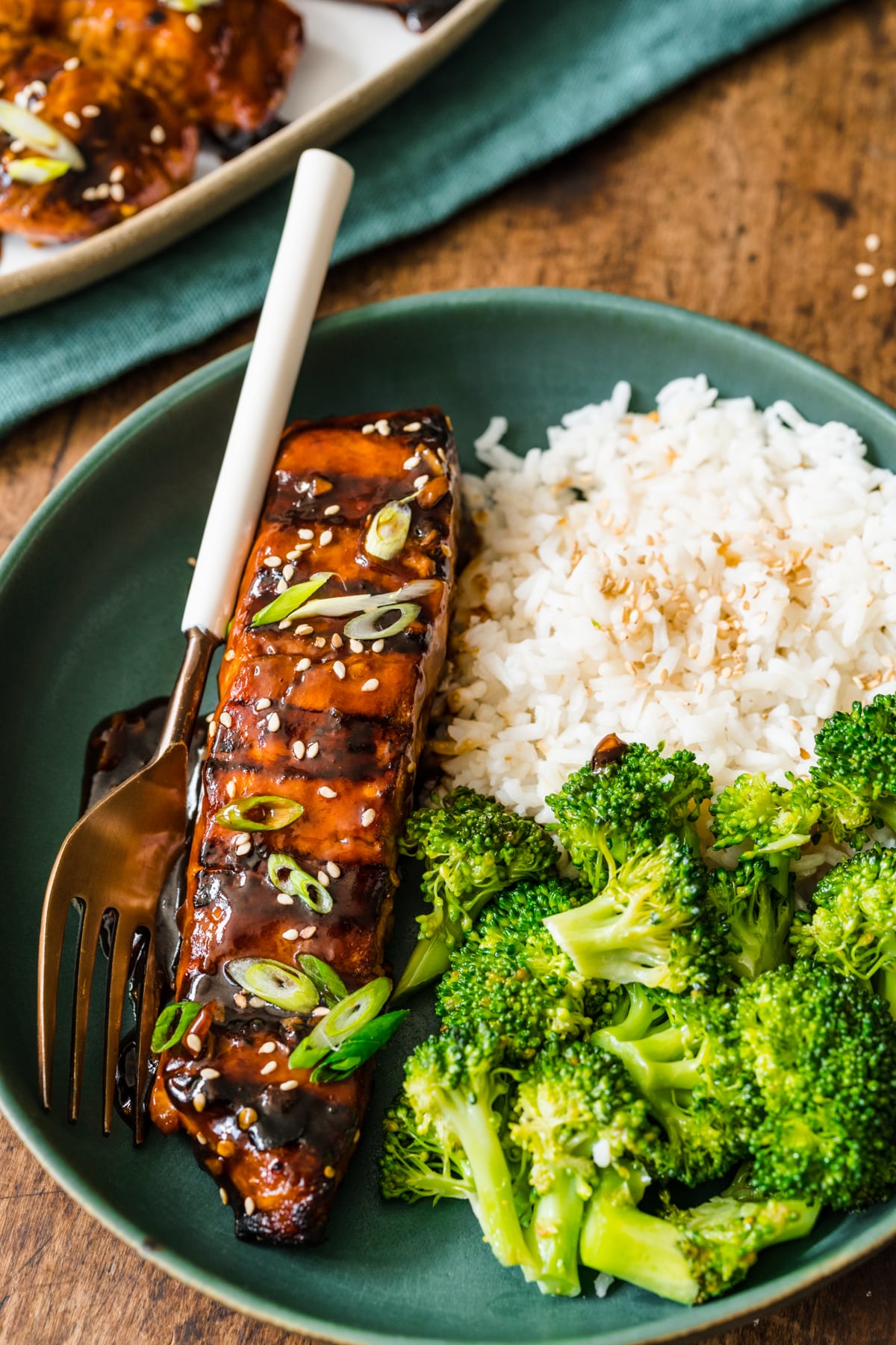 A plate of teriyaki salmon with a fork on it. 