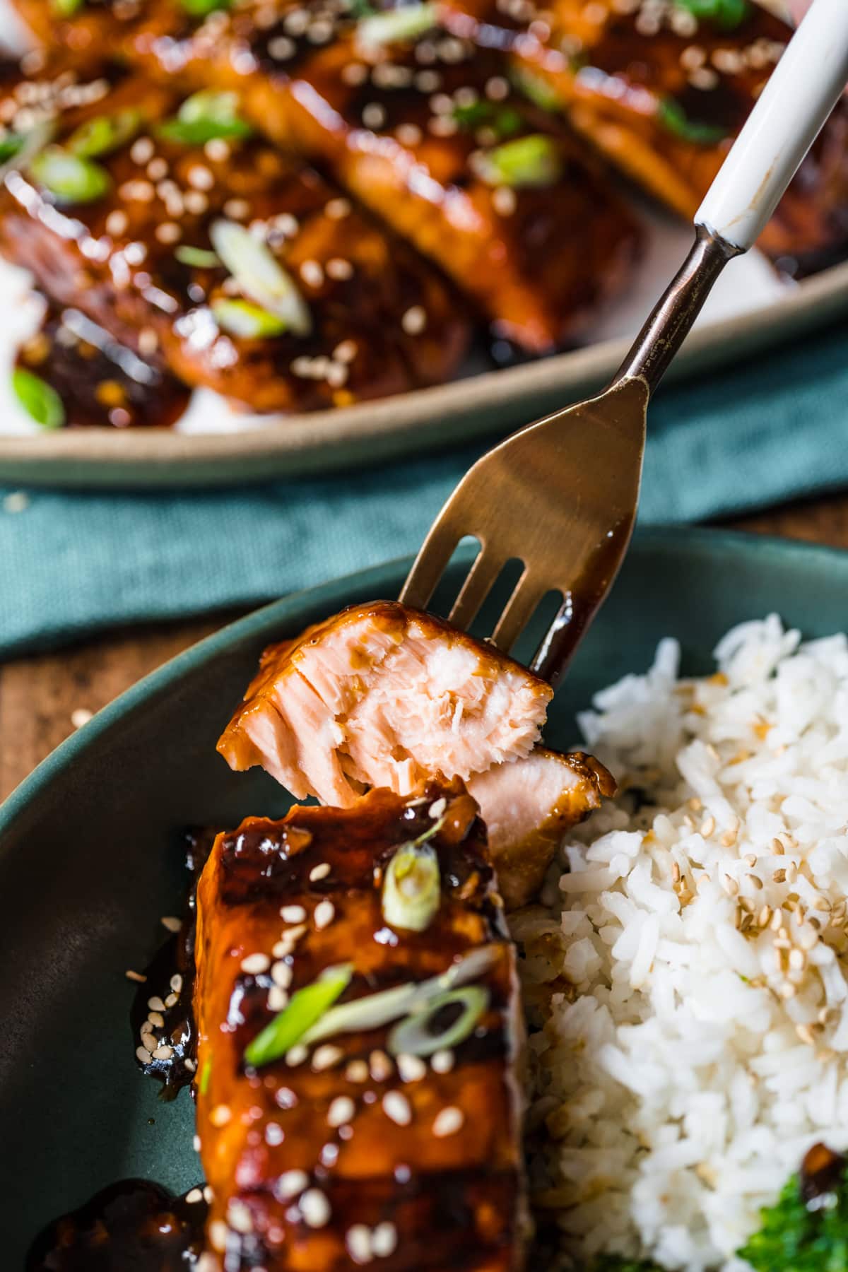 A fork taking a bite of teriyaki salmon.