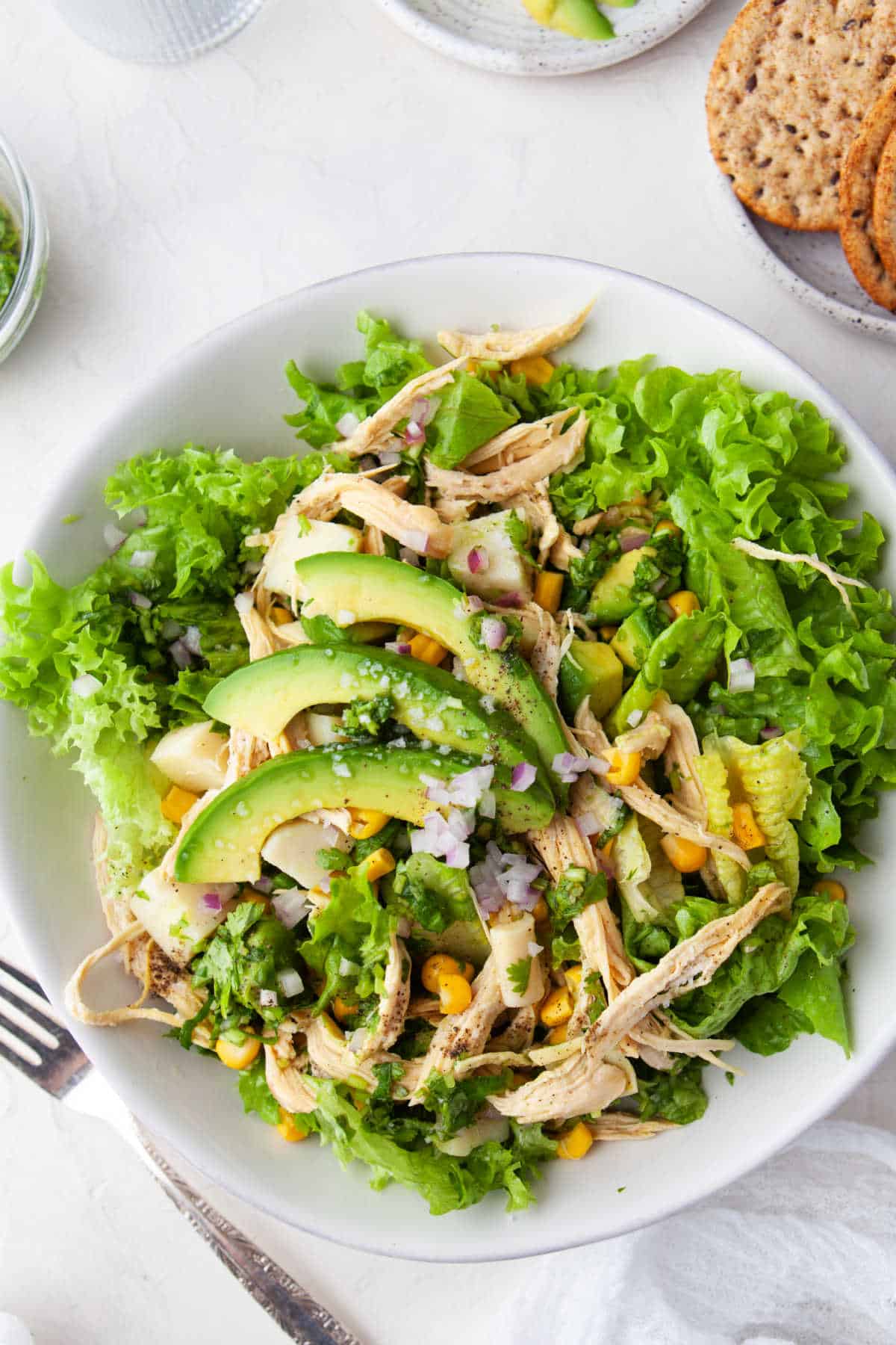 Avocado chicken salad next to a dish of crackers.