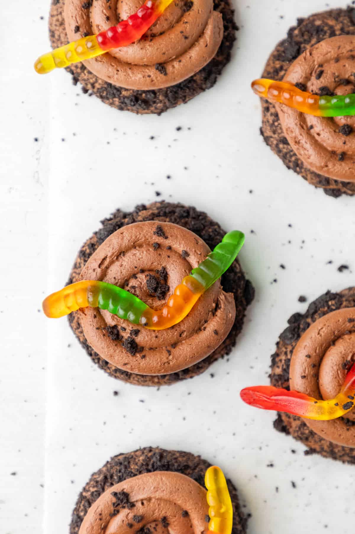 A chocolate dirt cookie topped with a green gummy worm. 