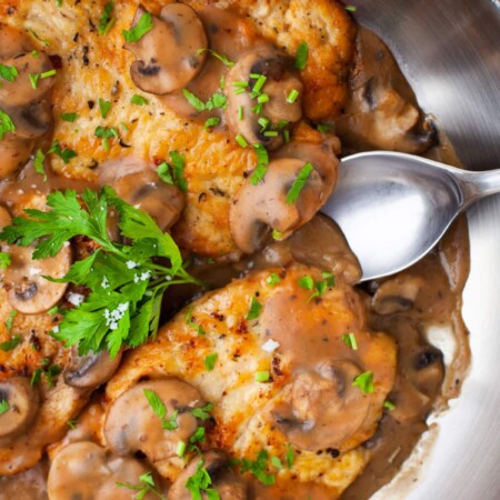 Silver spoon in a pan of chicken marsala.