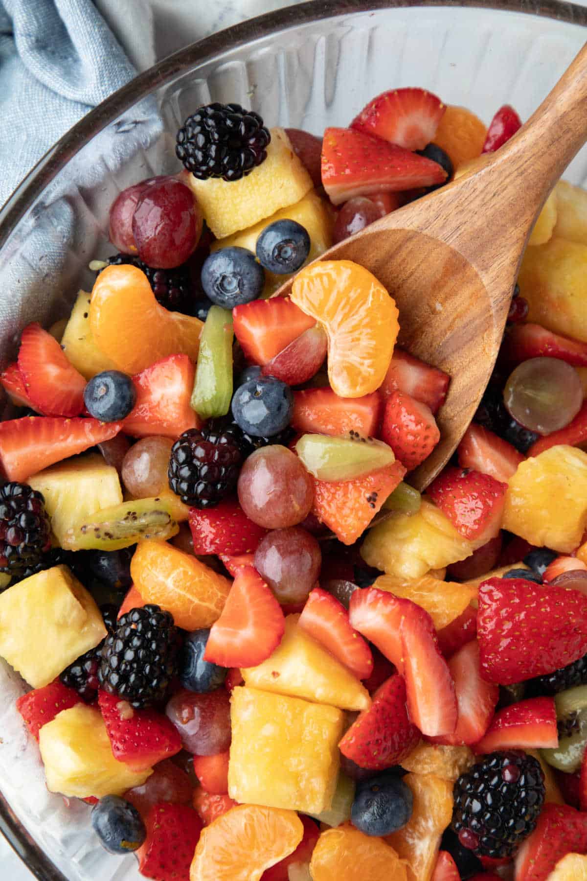 A wooden spoon scooping up fruit salad. 