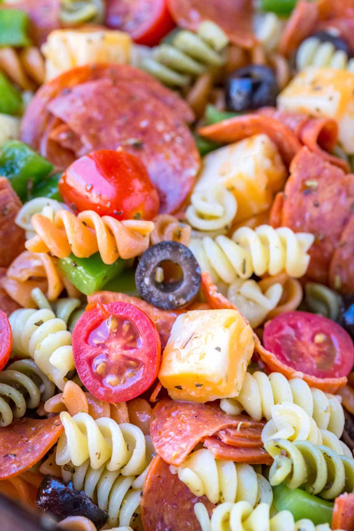 Pasta salad with pepperoni, olives, cheese, and tomatoes.