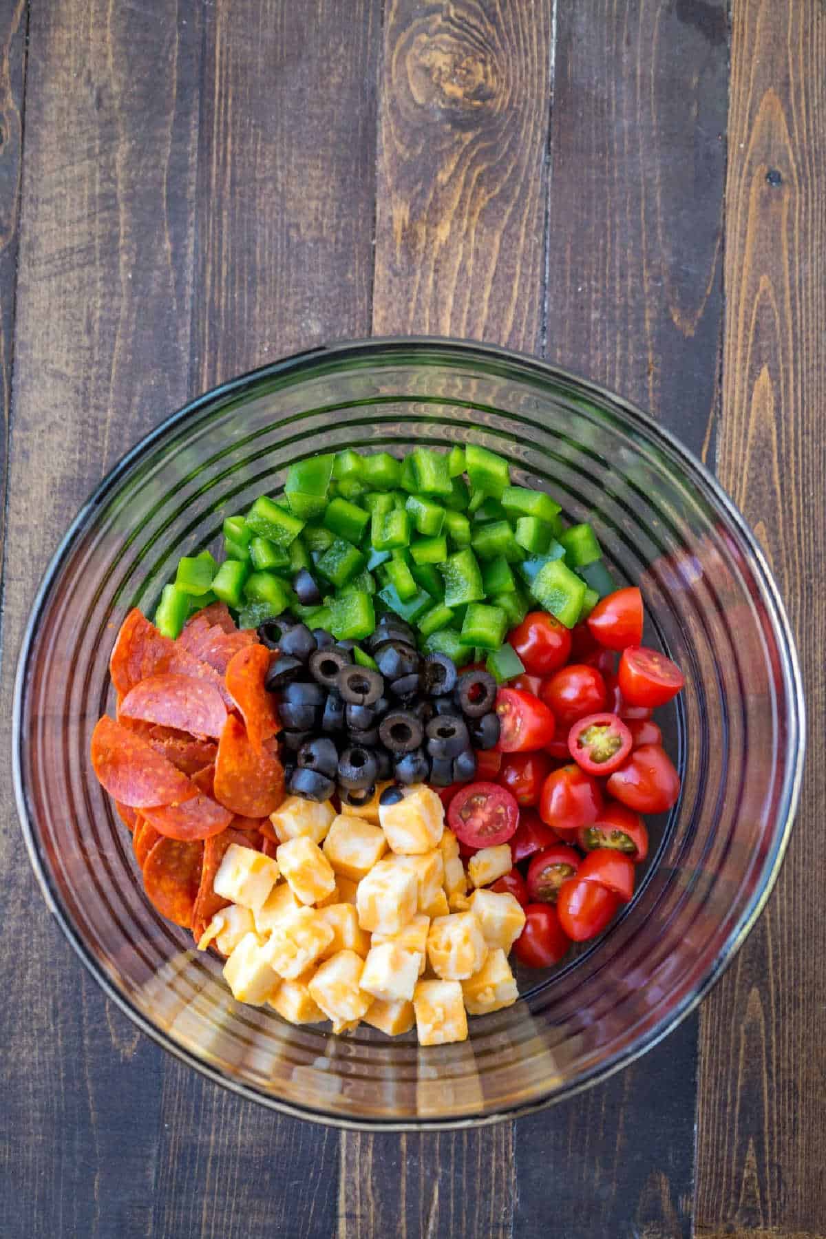 Vegetables and cheese in a glass mixing bowl. 