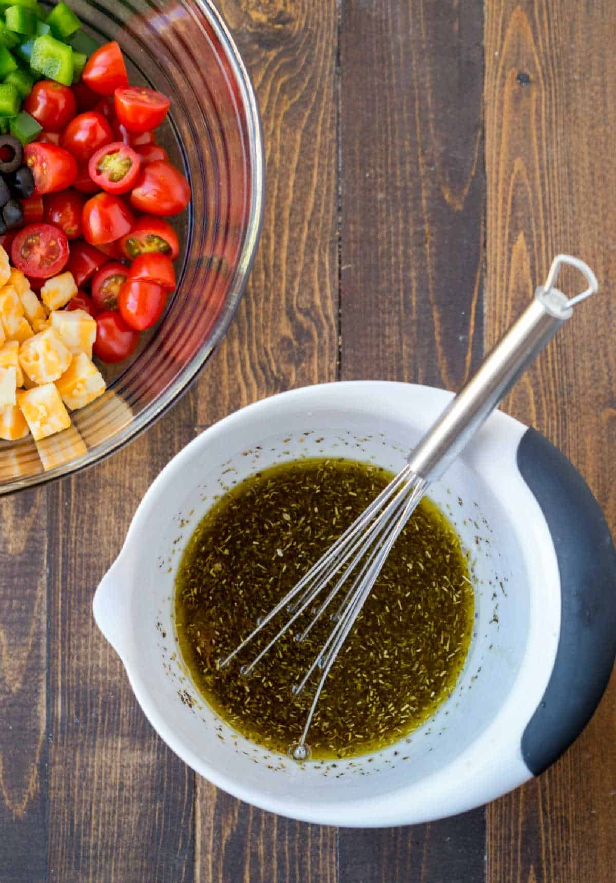 Homemade Italian dressing in a mixing bowl with a whisk.