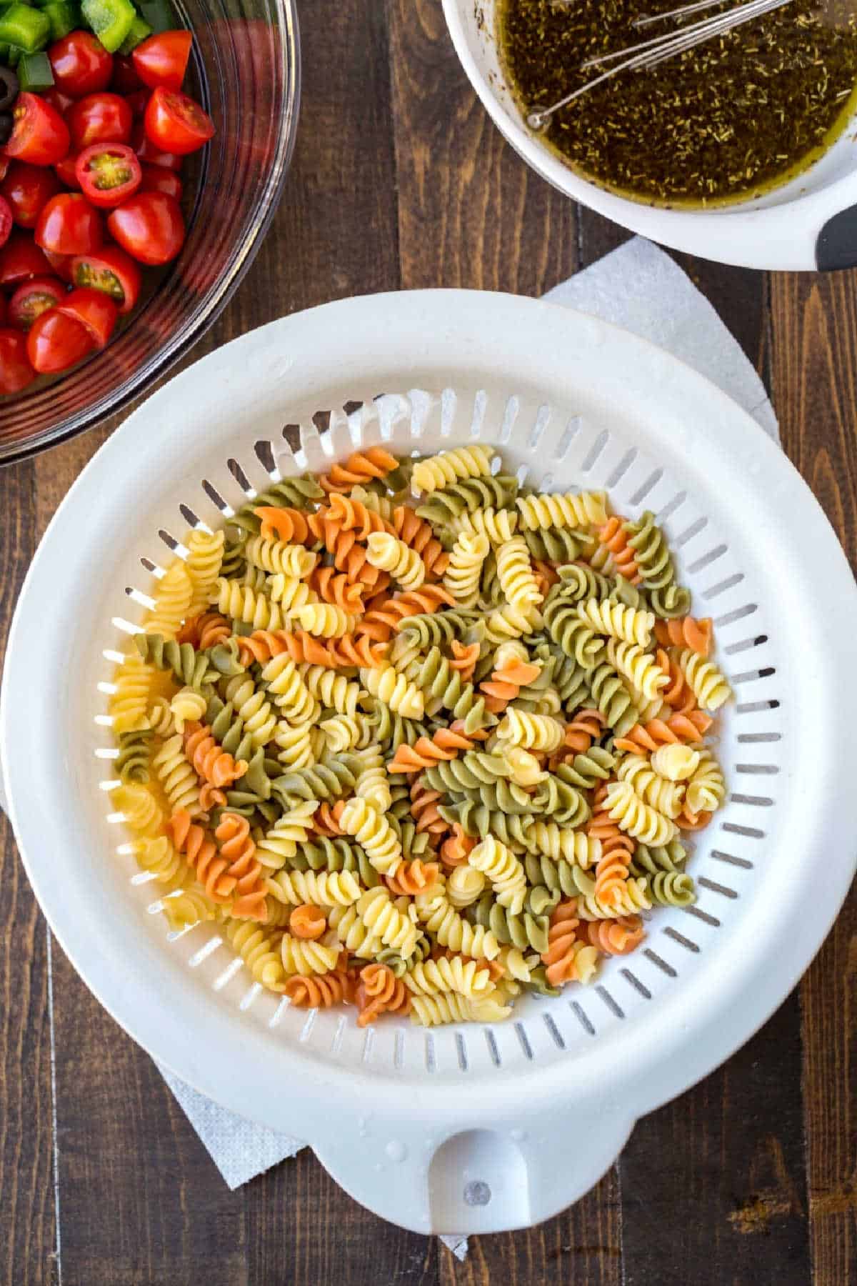 Cooked tricolor rotini in a white colander. 