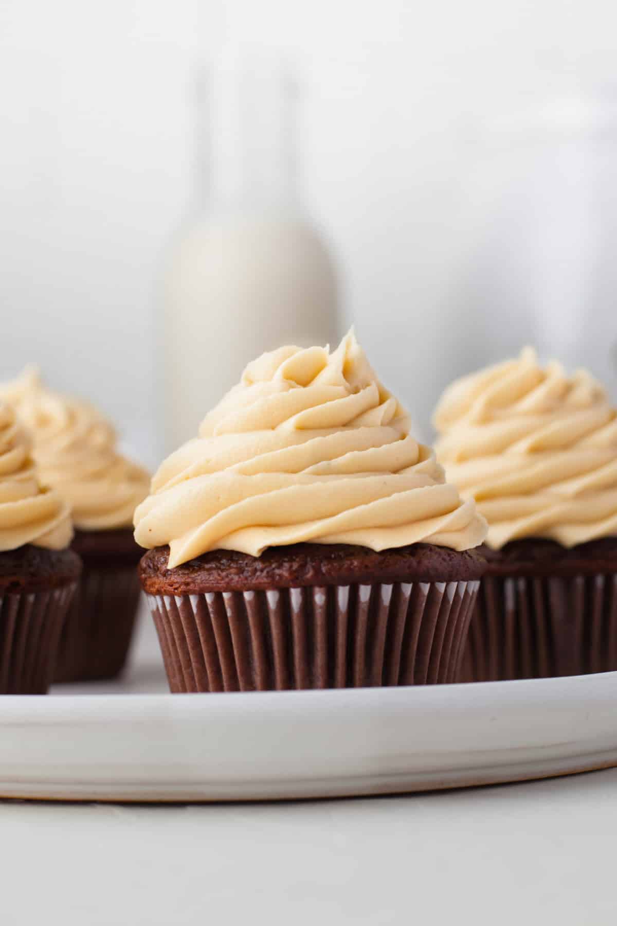 Four chocolate cupcakes topped with caramel buttercream frosting. 