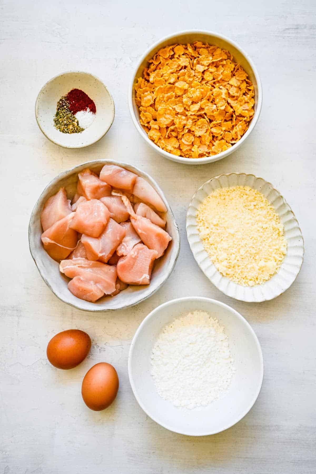 Ingredients for crunchy baked chicken nuggets in dishes.
