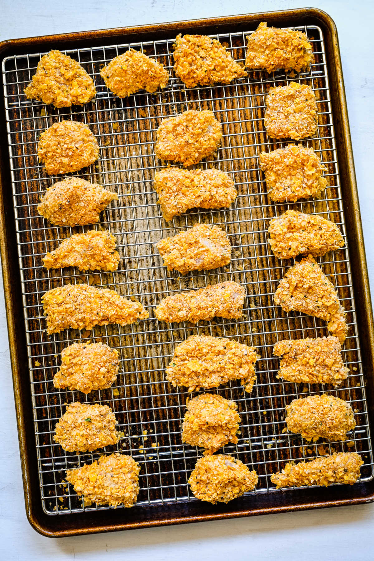 Pieces of cornflake coated chicken on a wire cooling rack. 