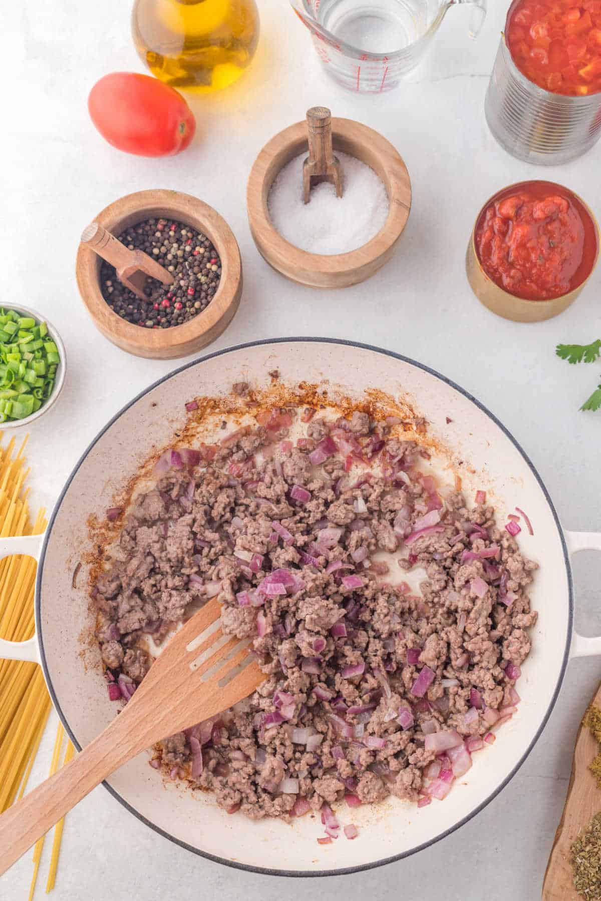 Ground beef and diced onion cooking in a skillet. 