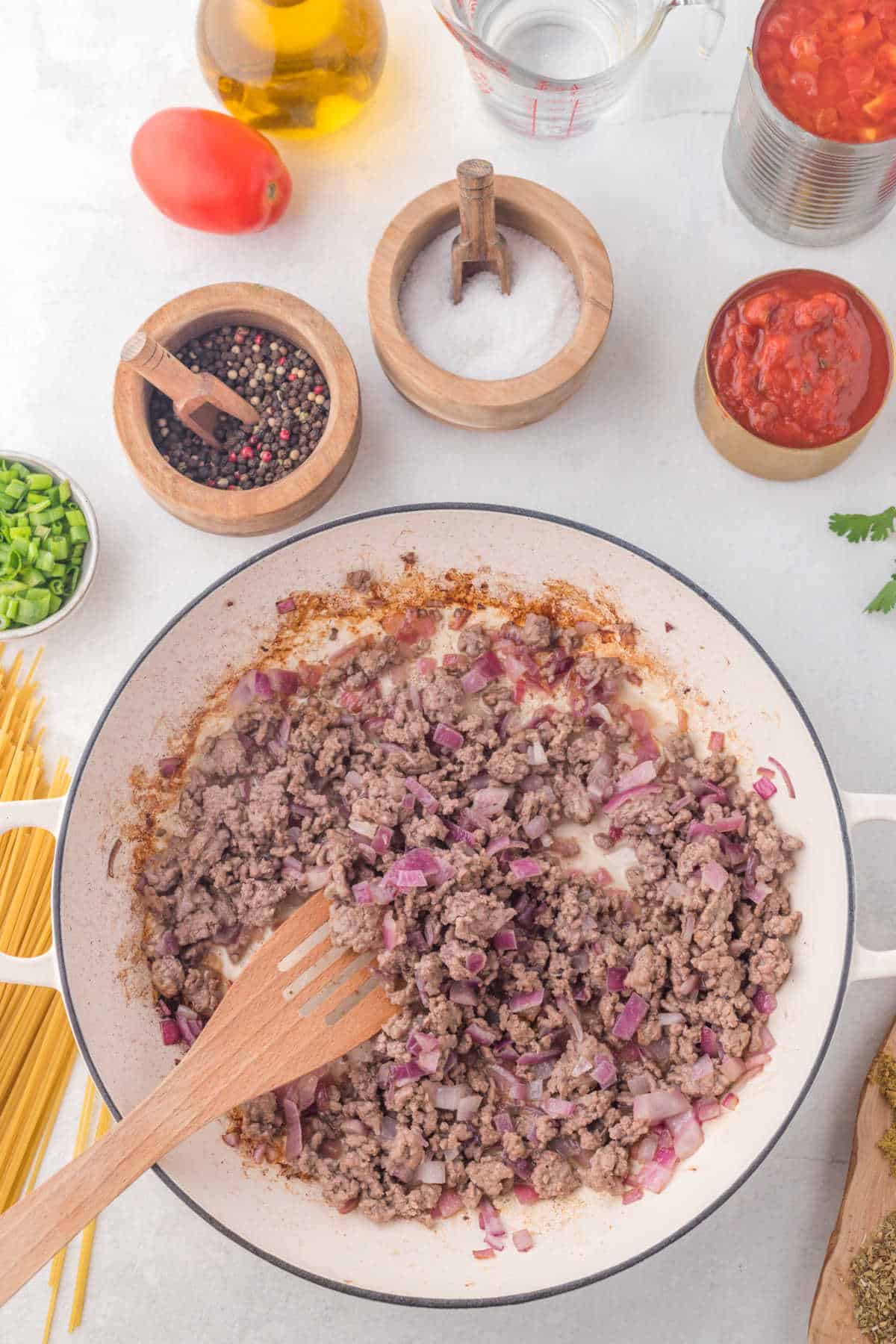 Ground beef and diced onion cooking in a skillet.