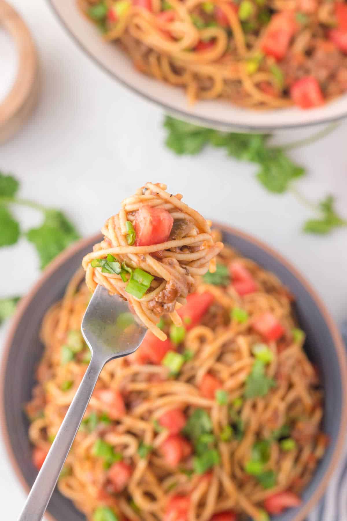 A fork holding a bite of taco spaghetti.