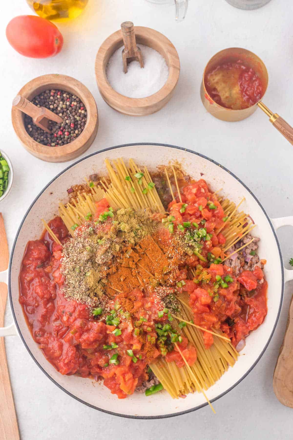 Spaghetti spices and tomatoes in a skillet. 