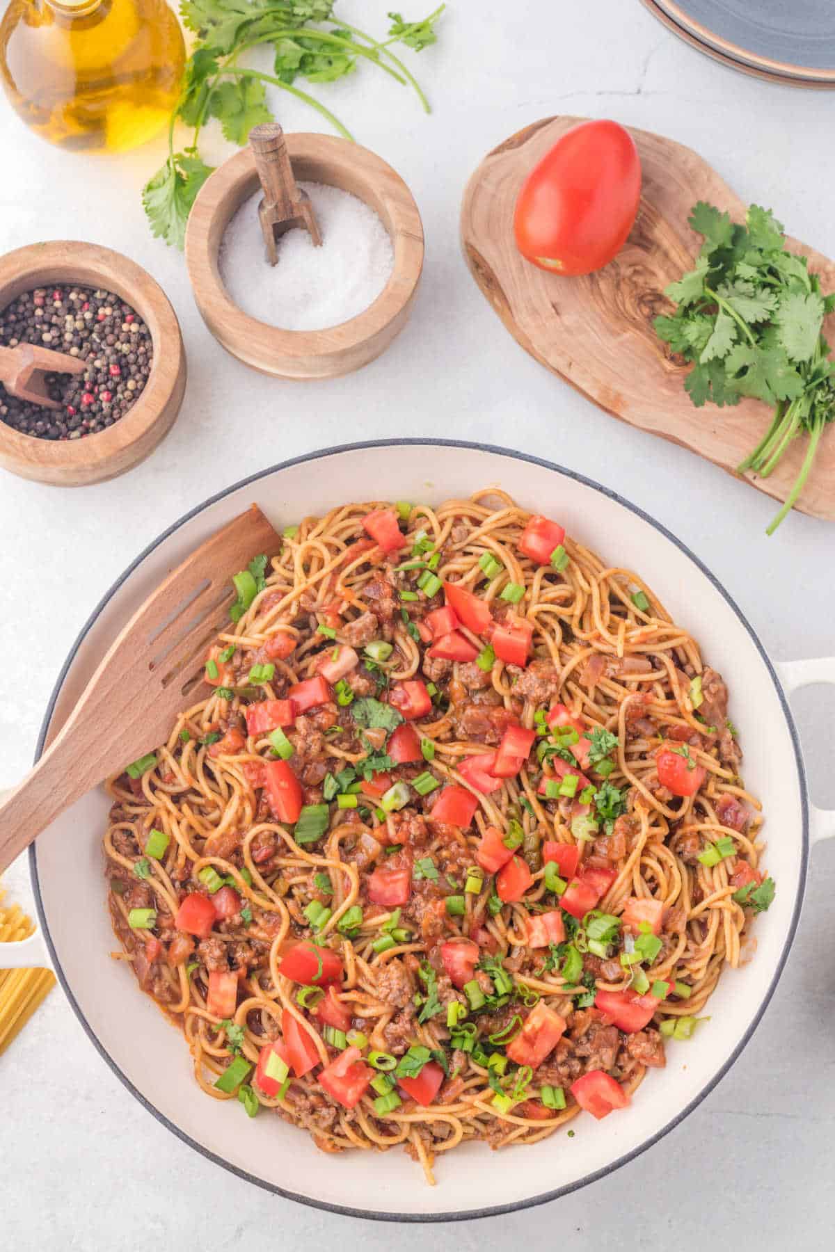 Taco spaghetti topped with diced tomato and green onion.