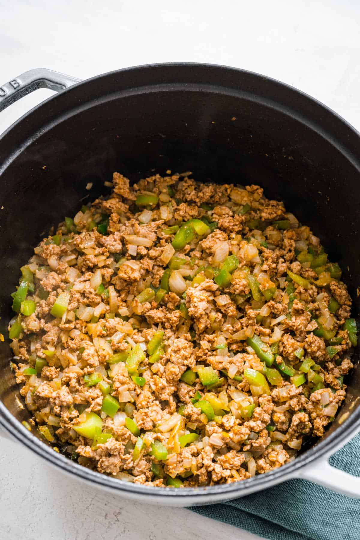 Ground turkey cooking with vegetables in a saucepot.