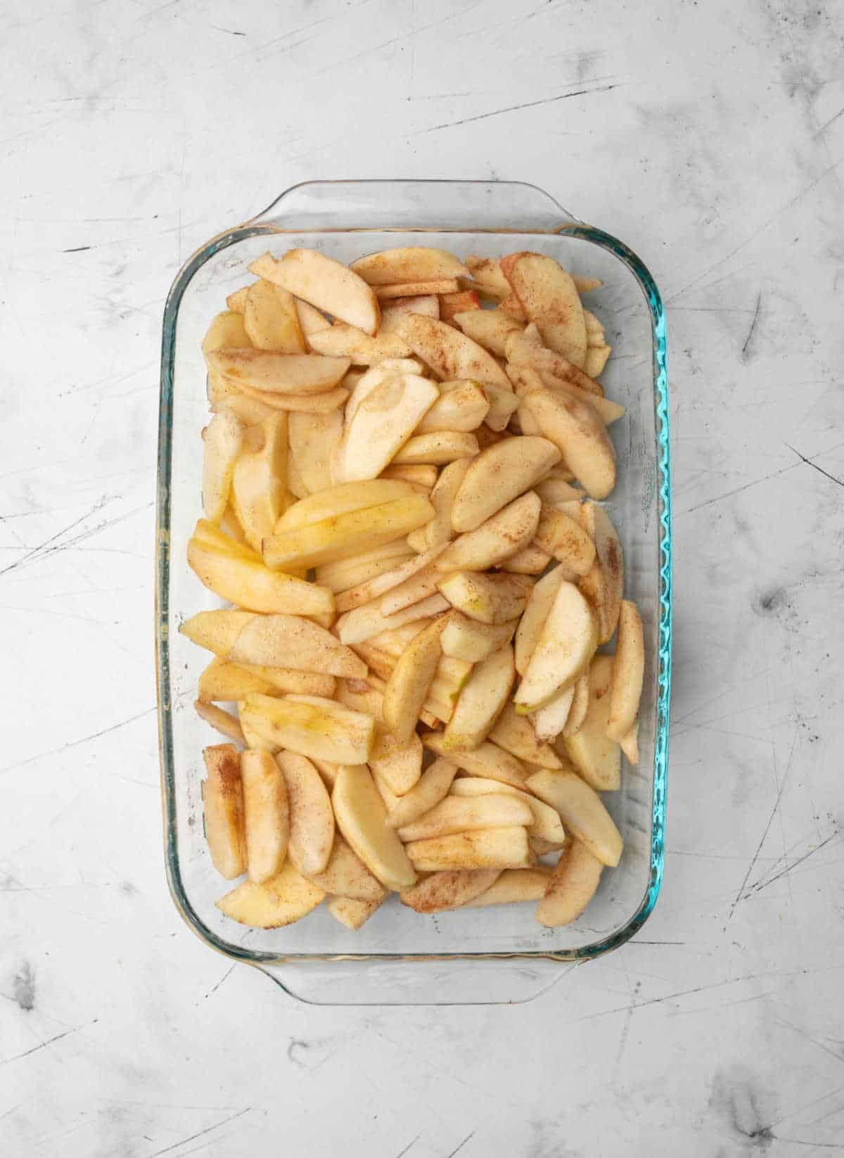 Apple slices in a glass baking pan. 