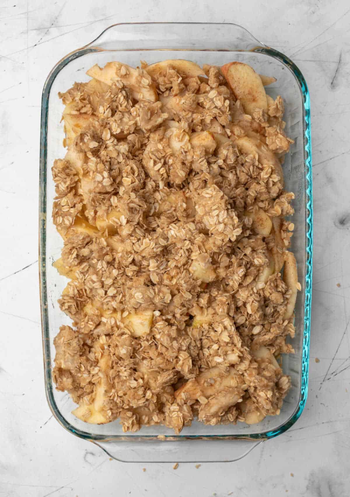 Unbaked apple crisp in a glass baking pan. 