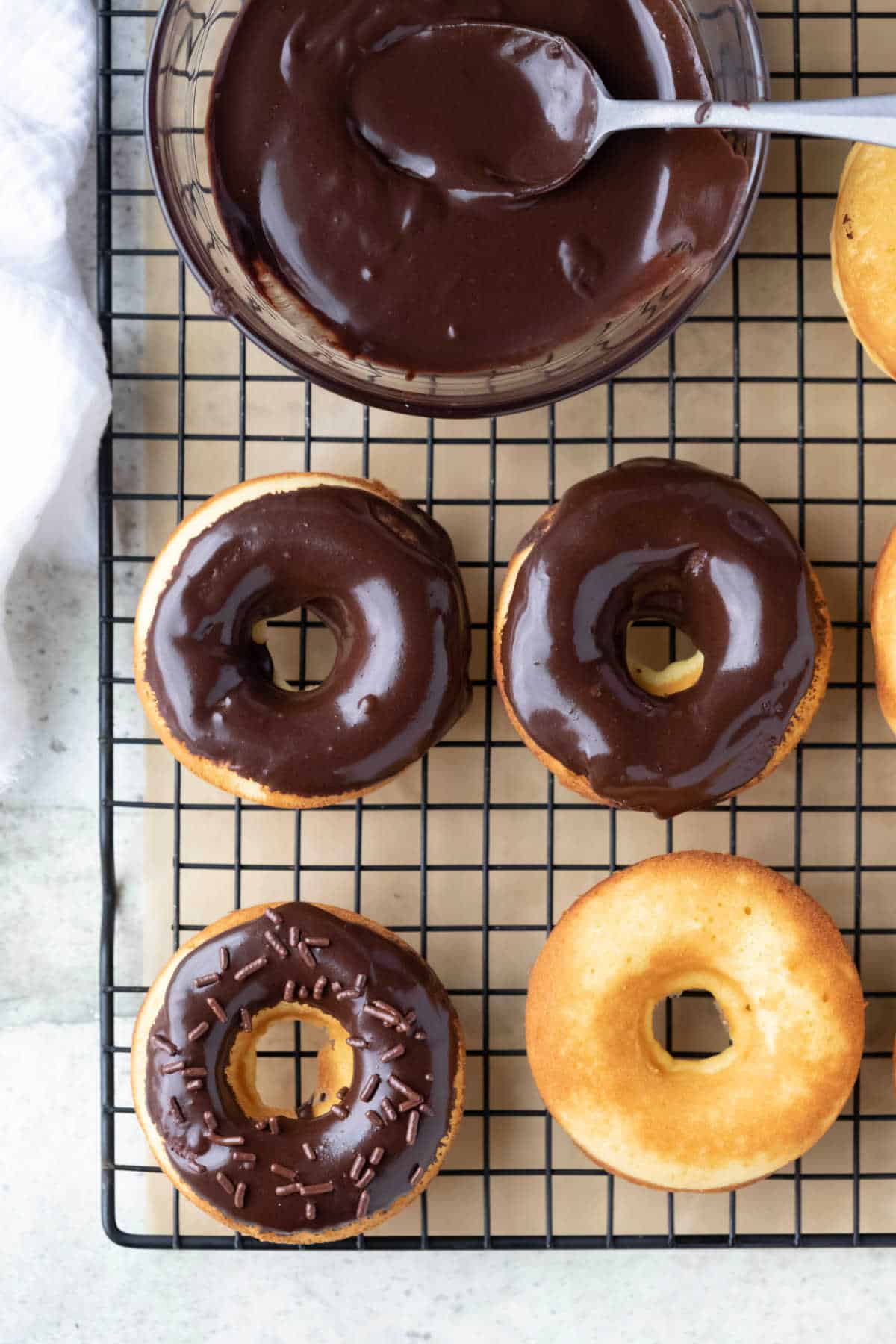 Overhead photo of chocolate glazed baked donuts on a wire cooling rack. 