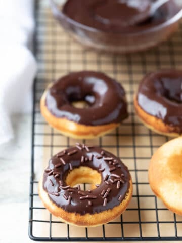 Baked donuts with chocolate glaze on a wire cooling rack.