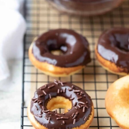 Baked donuts with chocolate glaze on a wire cooling rack.