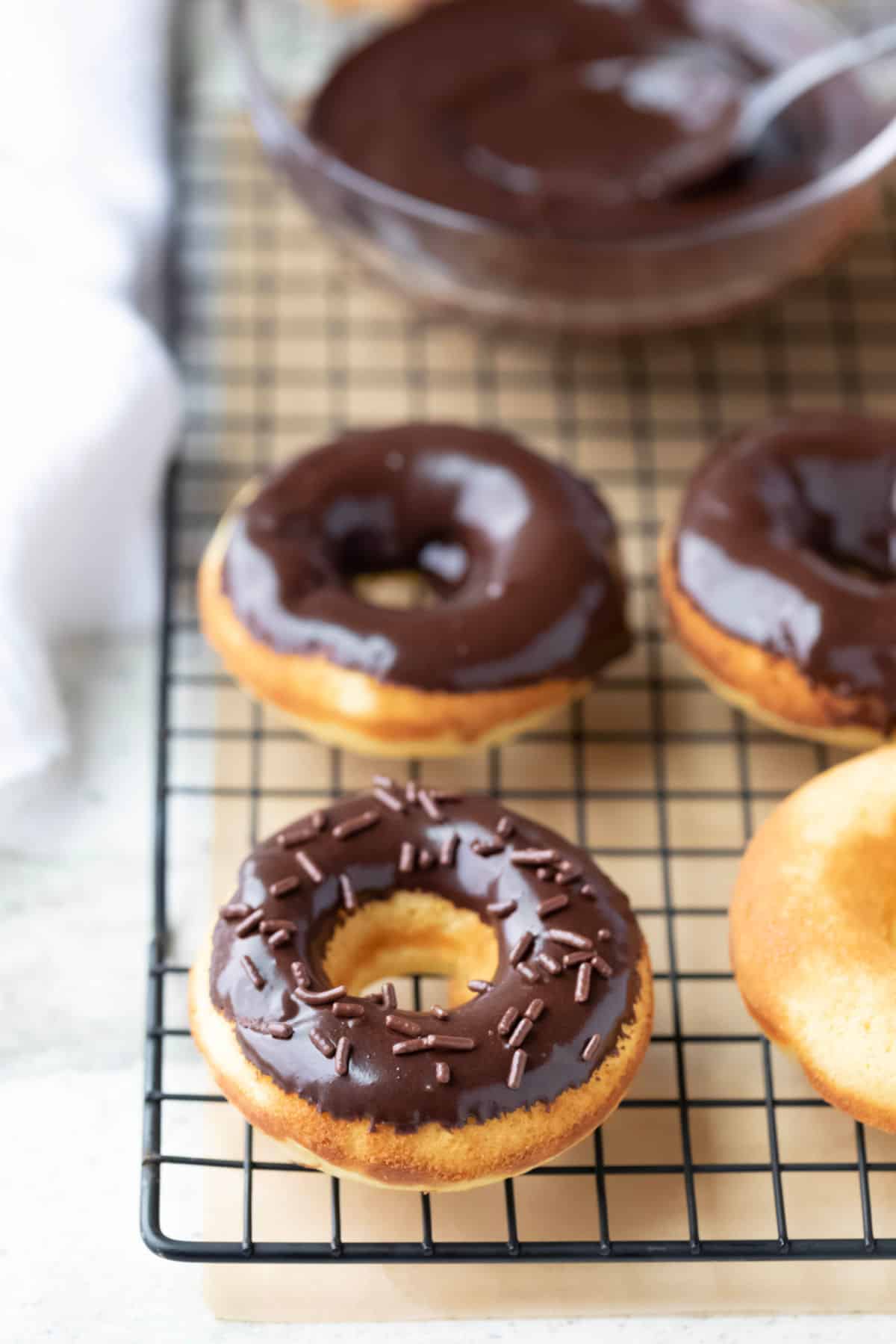 Baked donuts with chocolate glaze on a wire cooling rack.